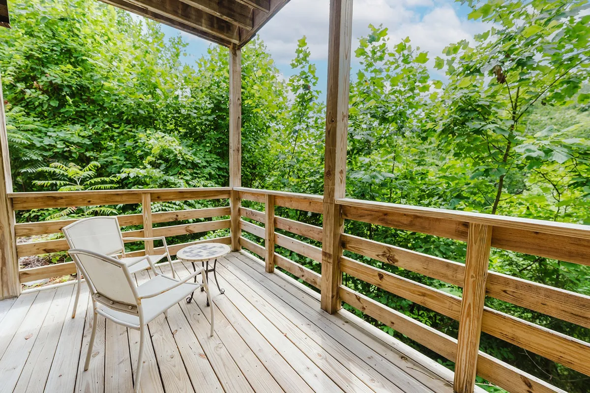 A cozy wooden deck with a lounge chair and small table sits nestled among vibrant greenery. The deck radiates tranquility and privacy, making it the perfect spot for couples to relax, read, or simply enjoy each other's company surrounded by nature.