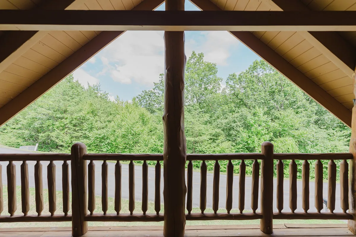 A tranquil balcony scene with wooden railings, a roof structure, and a peaceful view of surrounding trees. The setting invites quiet moments of wildlife watching, stargazing, or reading in the fresh mountain air.